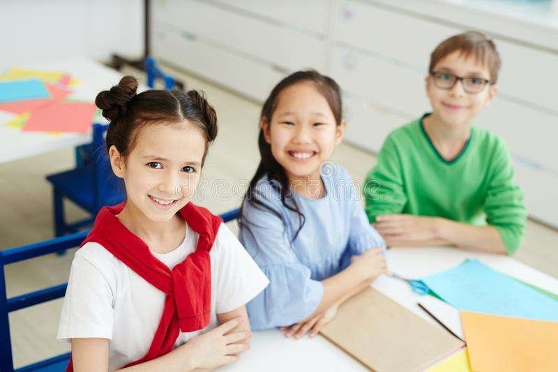 happy children art class portrait elementary school kids sitting desk colored paper smiling camera cheerfully 117730056